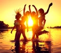 Beach party. Happy girls in water over sunset