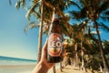 Beach party with popular thai Leo beer bottle in happy tourist hand under palms Royalty Free Stock Photo