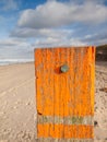 Beach post with sea level marker with beach and sea behind