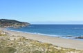 Beach with promenade, sand dunes with grass and blue sky. Arteixo, Coruna, Galicia, Spain.