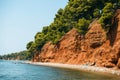 Beach with red land and green pines in Metamorfosi, Greece