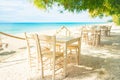 Beach restaurant with all white colored furniture in front of the fascinating golden turquoise colors of the sand and sea. Bright Royalty Free Stock Photo