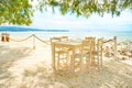 Beach restaurant with all white colored furniture in front of the fascinating golden turquoise colors of the sand and sea. Bright Royalty Free Stock Photo