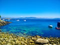 Beach of rocks in Cies Islands, Galicia, Spain, with boats diving in front of it Royalty Free Stock Photo