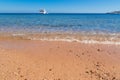 Beach with sand and light surf against the yacht in the sea