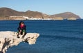 Young woman sitting on sculpted rock structure, Los Escullos, Spain Royalty Free Stock Photo