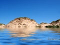 Beach from the sea at formby merseyside with tall sand dunes covered in rough grass and a blue summer sunlit sky