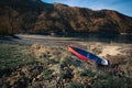 Beach of the sea with a small colorful boat with rocky mountains in the background