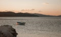 Beach by the sea at sunset with a lonely abandoned boat in the water. Mountains in the background. Travel Croatia Royalty Free Stock Photo