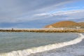 Beach season is over. Two lonely figures walking along the breakwater in Dzhubga on the background of the mountain `Hedgehog` Royalty Free Stock Photo