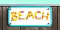 BEACH sign made of yellow pink red orange flower collage, enamel, metal or pottery beach sign, wooden wall. frame, turquoise sky Royalty Free Stock Photo