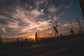 Beach sports: sports guys play volleyball at sunset. Beautiful clouds and colors of the sky. Royalty Free Stock Photo