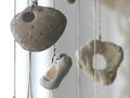 Beach stones with holes hanging on pieces of white twine in a window