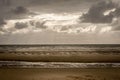 Beach on a stormy day with sun rays breaking through the clouds Royalty Free Stock Photo