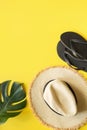 Beach straw sun hat, flip flops and monstera. Summer holiday background on yellow. View from above. Space for text Royalty Free Stock Photo