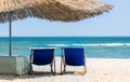 Beach straw umbrella from the sun on the beach with sun beds, on the background of the sea and blue sky. Royalty Free Stock Photo