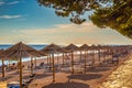 Beach with straw umbrellas at sunset near Primosten town, a popu Royalty Free Stock Photo