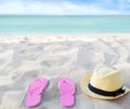 Beach summer holiday background. Flip flops and hat on sand near ocean. Summertime accessories on seaside. Tropical vacation Royalty Free Stock Photo