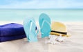 Beach summer holiday background. Flip flops, towels and hat on sand near ocean. Summertime accessories on seaside. Tropical Royalty Free Stock Photo