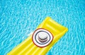 Beach summer holiday background. Inflatable air mattress and hat on swimming pool. Yellow lilo and summertime accessories on