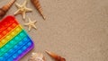 Beach summer vacation banner concept with trendy bright rainbow silicone stress relief toy.Colorful pop it toy,seashells and