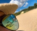 Beach with sun umbrellas and chair lounges reflection in woman sunglasses sitting on the beach at summer Royalty Free Stock Photo