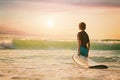 Back view of the little surfer boy surfing lifestyle relaxing holding surfboard looking at ocean waves for surf Royalty Free Stock Photo