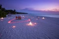 Beach sunset, couple table setting with candles and heart shape lights close to calm sea Royalty Free Stock Photo