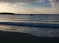 A beach at sunset with a fishing boat silluete