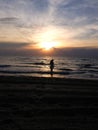 Beach sunset reflecting over dark waves with slim teenage girl Royalty Free Stock Photo