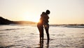 Beach, sunset and silhouette of couple hug, connect and enjoy romantic time together, bonding and relax in sea water Royalty Free Stock Photo