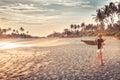 Beach sunset travel vacation lifestyle landscape with woman on wide sand coastline with palm trees with scenic orange sunset sky Royalty Free Stock Photo