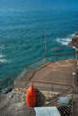 a beach terrace made of planks on the shore with rocks of the Mediterranean Sea, a red lifeboat Royalty Free Stock Photo