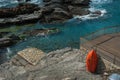 a beach terrace made of planks on the shore with rocks of the Mediterranean Sea, a red lifeboat