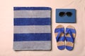 Beach towel, book, sunglasses and flip flops on sand, flat lay