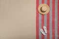 Beach towel, flip flops and hat on sand, top view. Space for text Royalty Free Stock Photo