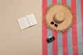 Beach towel, hat, sunglasses, camera and open book on sand, flat lay Royalty Free Stock Photo
