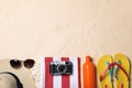 Beach towel, hat, sunglasses, camera, sunscreen and flip flops on sand, flat lay. Space for text Royalty Free Stock Photo
