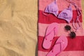 Beach towel with slippers, sunglasses and swimsuit on sand, top view. Space for text Royalty Free Stock Photo