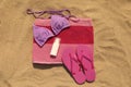 Beach towel with slippers, sunscreen and swimsuit on sand, flat lay Royalty Free Stock Photo