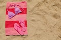 Beach towel with slippers and swimsuit on sand, top view. Space for text Royalty Free Stock Photo