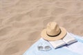 Beach towel with straw hat, sunglasses and book on sand. Space for text Royalty Free Stock Photo