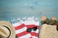 Beach towel, sunglasses, hat and straw bag with slippers on light blue wooden background, flat lay. Space for text Royalty Free Stock Photo