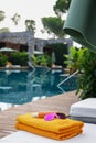 Beach towels, sunglasses and sunscreen on sun lounger near outdoor swimming pool, space for text. Luxury resort