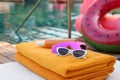 Beach towels, sunglasses and sunscreen on sunbed near outdoor swimming pool. Luxury resort