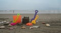 Beach toys, shovels and bucket on the sand surrounded by shells with the sea and blue sky in the background Royalty Free Stock Photo