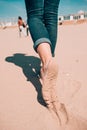 Beach travel - woman in a jeanse walking on sand beach leaving footprints in the sand. Closeup detail of female feet and Royalty Free Stock Photo