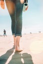 Beach travel - woman in a jeanse walking on sand beach leaving footprints in the sand. Closeup detail of female feet and Royalty Free Stock Photo