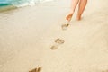 A Beach travel - woman relaxing walking on a sandy beach leaving footprints in the sand. Close up detail of female feet on golden Royalty Free Stock Photo