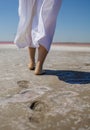 Beach travel - woman walking on sand beach leaving footprints in the sand. Closeup detail of female feet and golden sand beach Royalty Free Stock Photo